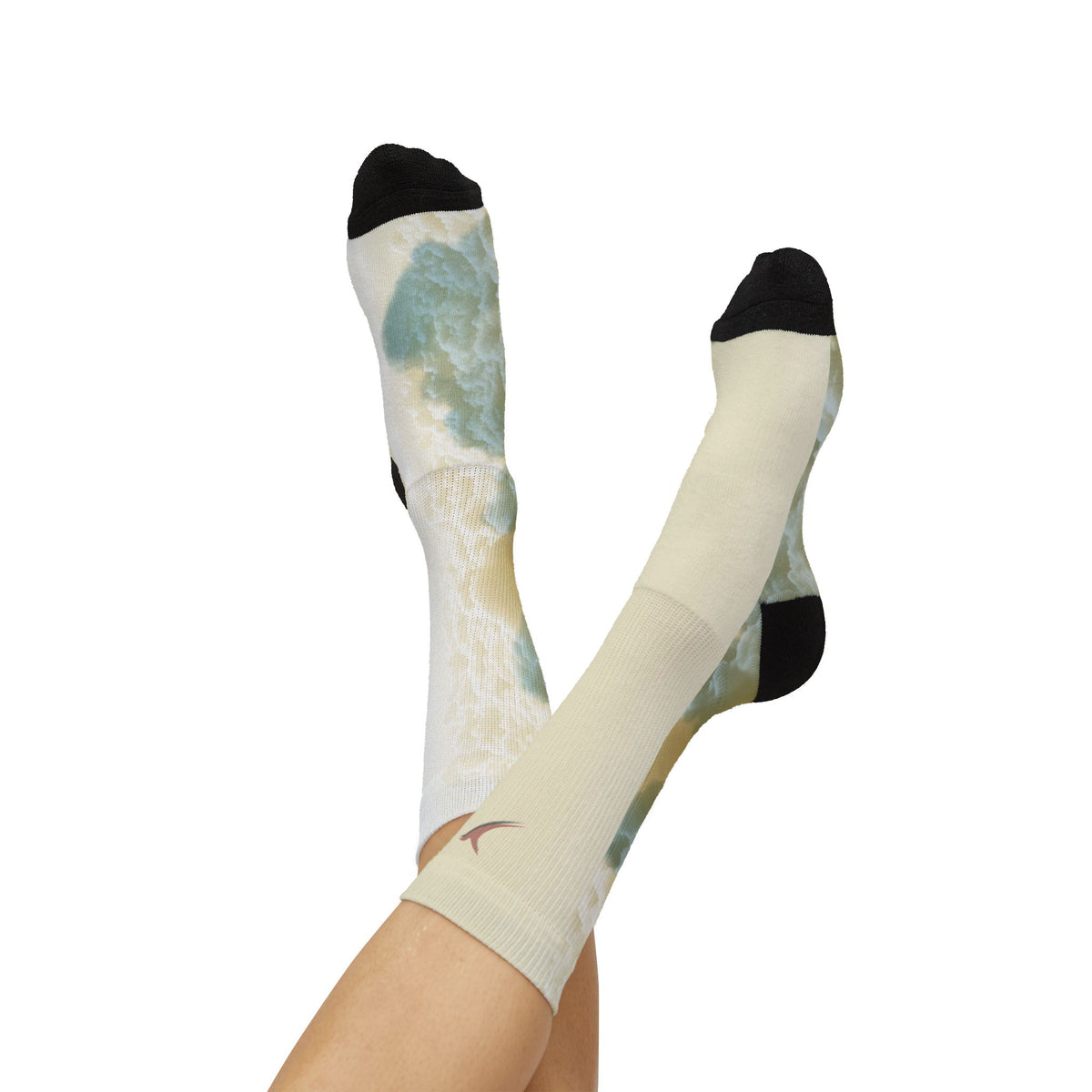 Nurse Crew Socks in cream and pale gold — golden cloud print with black toe and heel, small terracotta bird at the cuff — worn view with feet raised
